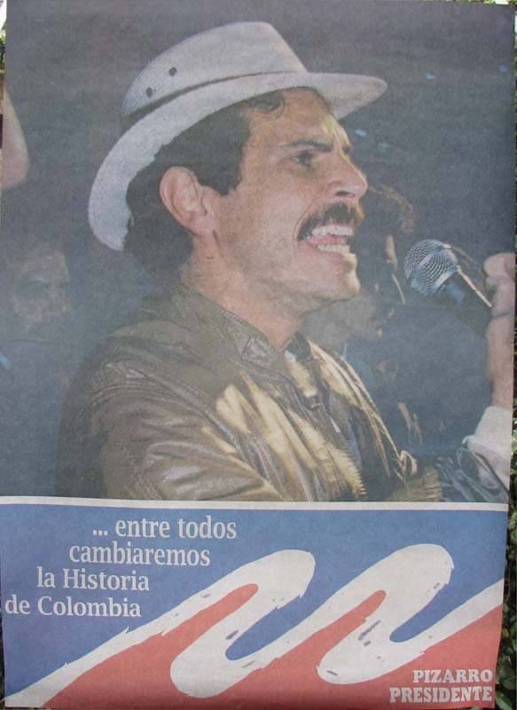 Afiche de Carlos Pizarro con sombrero y micrófono, y el lema «entre todos cambiaremos la historia de Colombia».