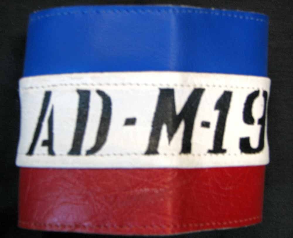Brazalete azul, blanco y rojo con las letras AD-M19.